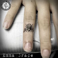 a small spider tattoo on the middle finger and ring tattoos is shown in black ink