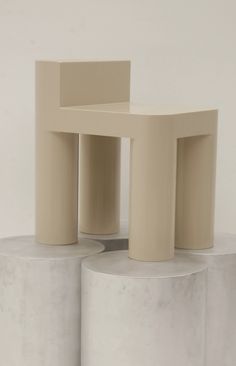 two white stools sitting next to each other on top of cement pillars in front of a white wall