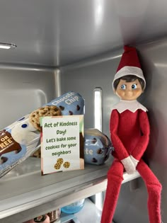 an elf is sitting on the shelf next to some cookies