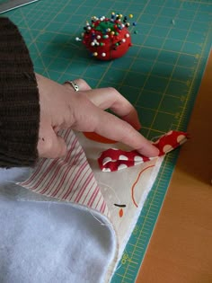 a person cutting fabric on top of a table next to a red ball and scissors