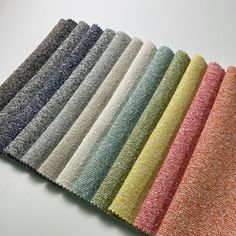 several colors of fabric laid out on a white table top, all lined up in rows