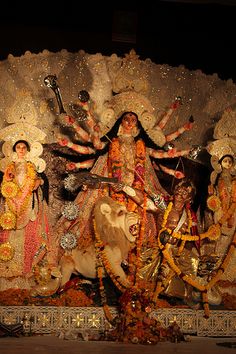 an idol is displayed in front of a stage with people dressed as hindu deities and animals