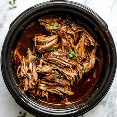 a pot filled with meat and sauce on top of a table