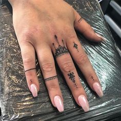 a woman's hand with tattoos on it and a crown tattooed on the middle finger