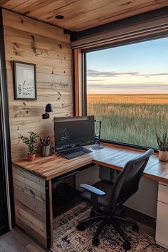 a desk with a laptop computer on it in front of a window overlooking the field