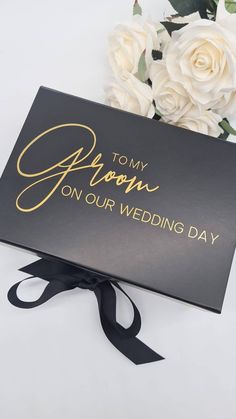 a bouquet of white roses sitting next to a black box that says, tomy crown on our wedding day