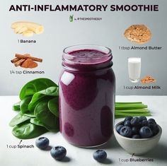 a glass jar filled with blueberry smoothie surrounded by ingredients