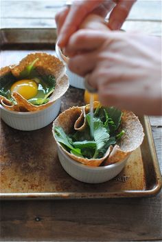 someone is dipping an egg into some food in small bowls on a tray with another person's hand