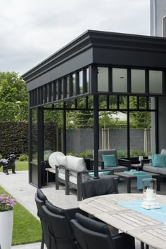 an outdoor dining area with chairs, tables and couches on the patio in front of a house