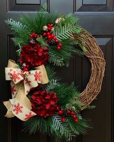 a christmas wreath with red flowers and pine cones