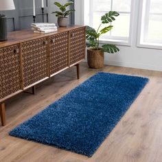 a living room with a blue rug on the floor next to a wooden sideboard