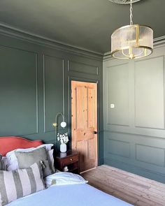 a bedroom with green painted walls and a bed in the middle, along with a wooden table