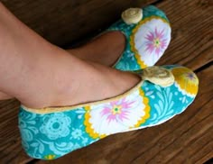 a woman's feet wearing blue and yellow shoes with flowers on the soles