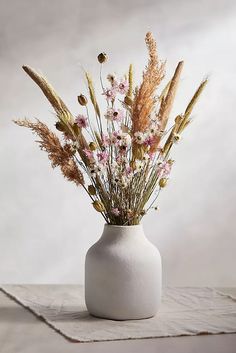 a white vase filled with flowers on top of a table