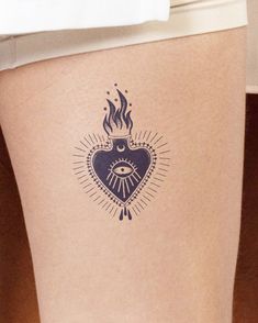 a woman's thigh with a tattoo on it that has an evil heart and eye