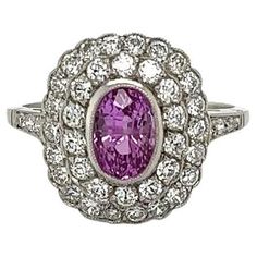 an oval shaped pink sapphire and diamond ring with white diamonds around the band, set in 18k white gold