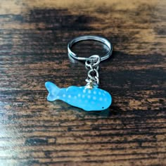 a blue fish keychain sitting on top of a wooden table