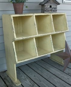 an old yellow bookcase with six cubbys on the bottom and two star shaped planters next to it