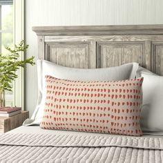 an orange and white pillow sitting on top of a bed next to a wooden headboard