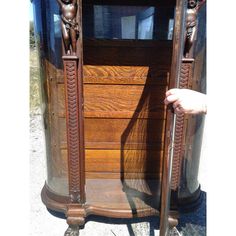 a wooden cabinet with carvings on the front and sides, holding two skis in it's hands