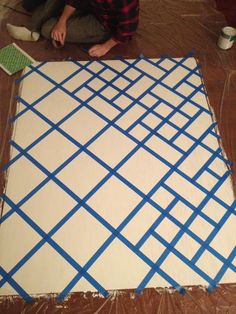 someone is painting the floor in blue and white squares on it's canvass