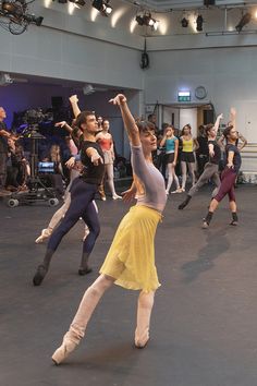 a group of young women dancing in a large room with lots of people watching them