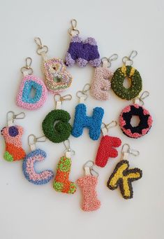 crocheted letters and numbers are arranged in the shape of keychains on a white surface