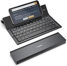 an open laptop computer sitting on top of a wireless keyboard next to a smaller device