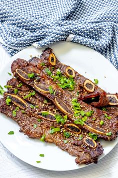 a white plate topped with steak covered in sauce and garnished with green onions