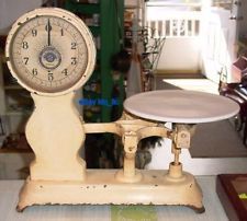 an old fashioned scale with a clock on it's side sitting on a table