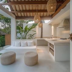 an outdoor kitchen and living room area with white couches, tables, and lights