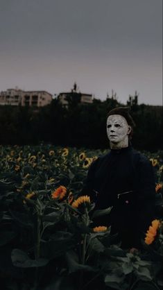 a person wearing a mask standing in a field of sunflowers