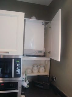 a kitchen with white cabinets and stainless steel appliances, including a microwave in the corner