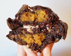 a hand holding a chocolate chip cookie with marshmallows and chocolate sauce on top