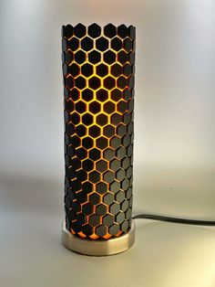 a lamp that is sitting on top of a table next to a light bulb in the shape of a honeycomb