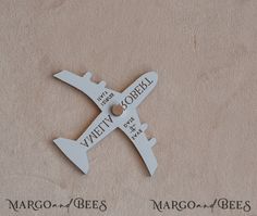 an airplane shaped ornament with two names attached to it's sides on a beige background