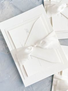 the wedding stationery is laid out on top of each other and tied with a white ribbon