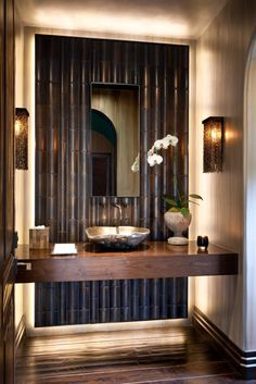 a bathroom sink sitting under a mirror on top of a wooden counter next to a doorway