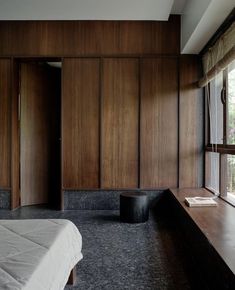 a bed sitting next to a window in a room with wood paneling on the walls