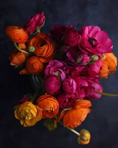 an arrangement of flowers in a vase on a dark background with space for text or image