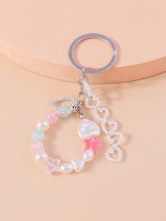 a keychain that says love with pearls and charms around it on top of a table