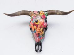 a bull's skull with long horns decorated with flowers and other things on it