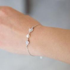 a woman's arm wearing a bracelet with pearls and leaves on the clasps