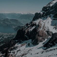 snow covered mountains and trees in the foreground, with a body of water in the distance