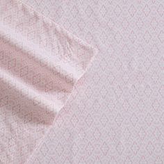 the pink and white bedding is made up with an intricate pattern on it's side