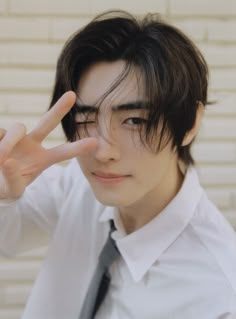 a young man making the peace sign with his hand while wearing a white shirt and tie