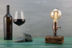 a light bulb sitting on top of a wooden block next to a glass of wine