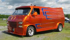 an orange and blue truck parked on top of a grass covered field