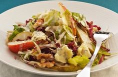 a white plate topped with salad next to a fork