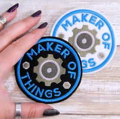 two circular patches with the words maker of things printed on them, one being a hand